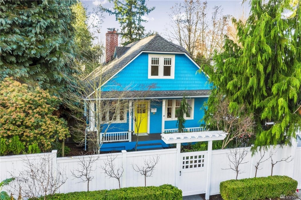 Blue home in the Maple Leaf neighborhood featuring a porch and a white fence