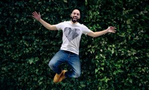 A man wearing a T-shirt with a heart on it is jumping