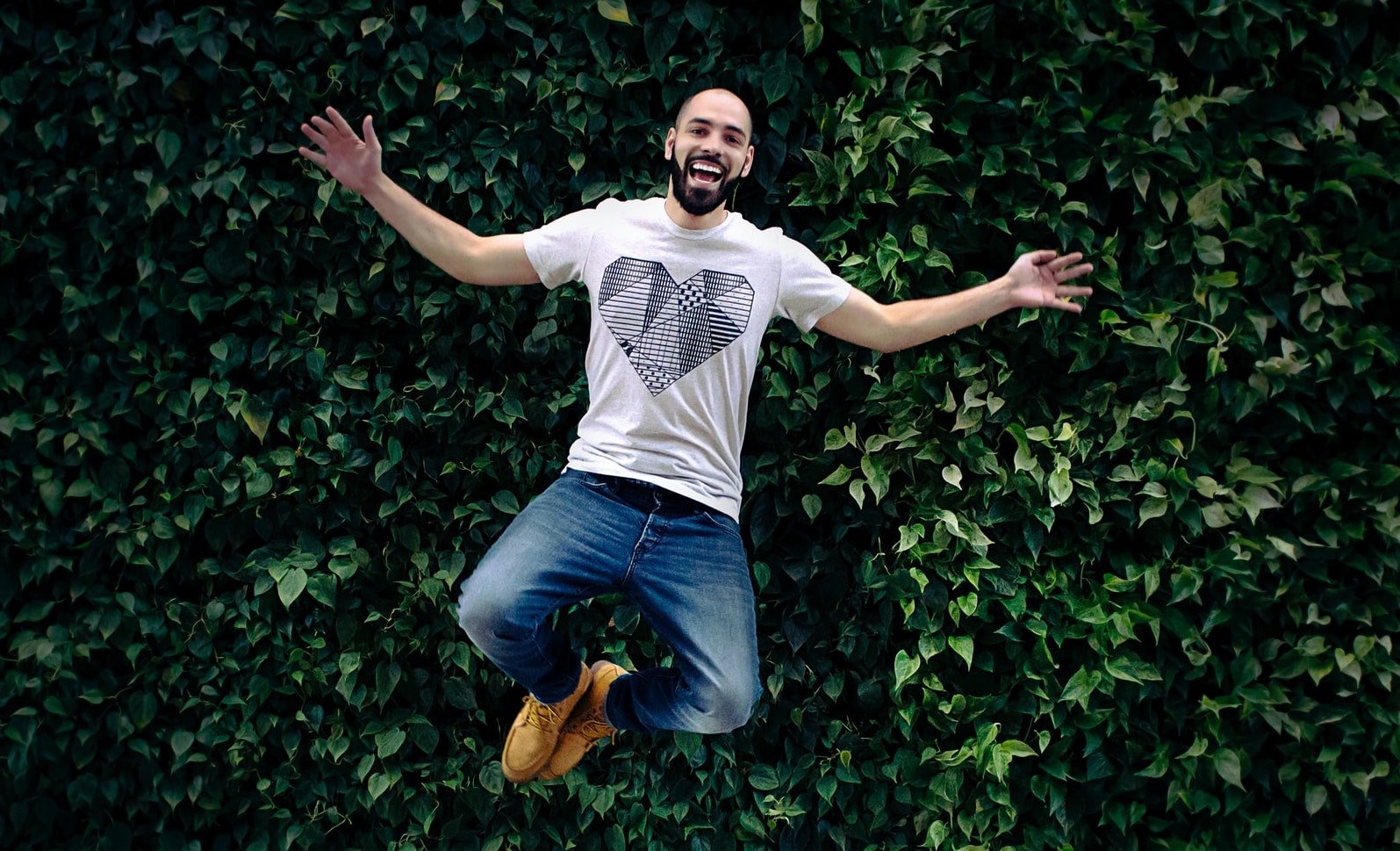 A man wearing a T-shirt with a heart on it is jumping 