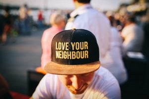 A man is wearing a hat that says "love your neighbour"