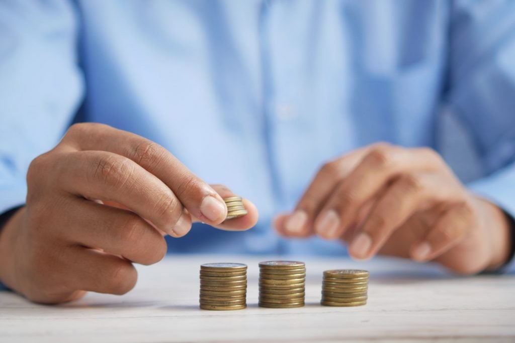 A person is counting coins in three stacks