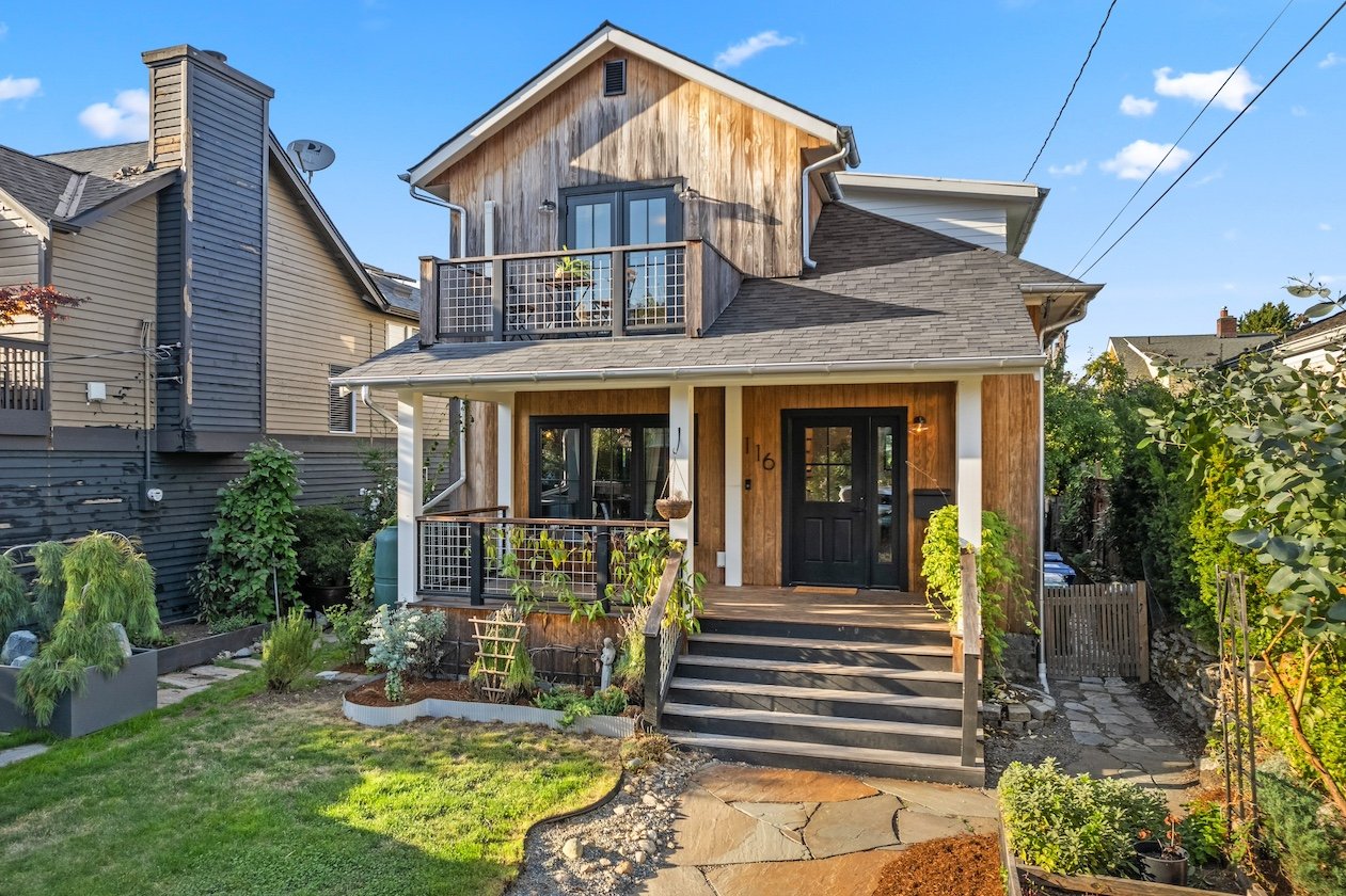 The front exterior of 116 NE 58th St shows the beautiful wood siding and manicured garden