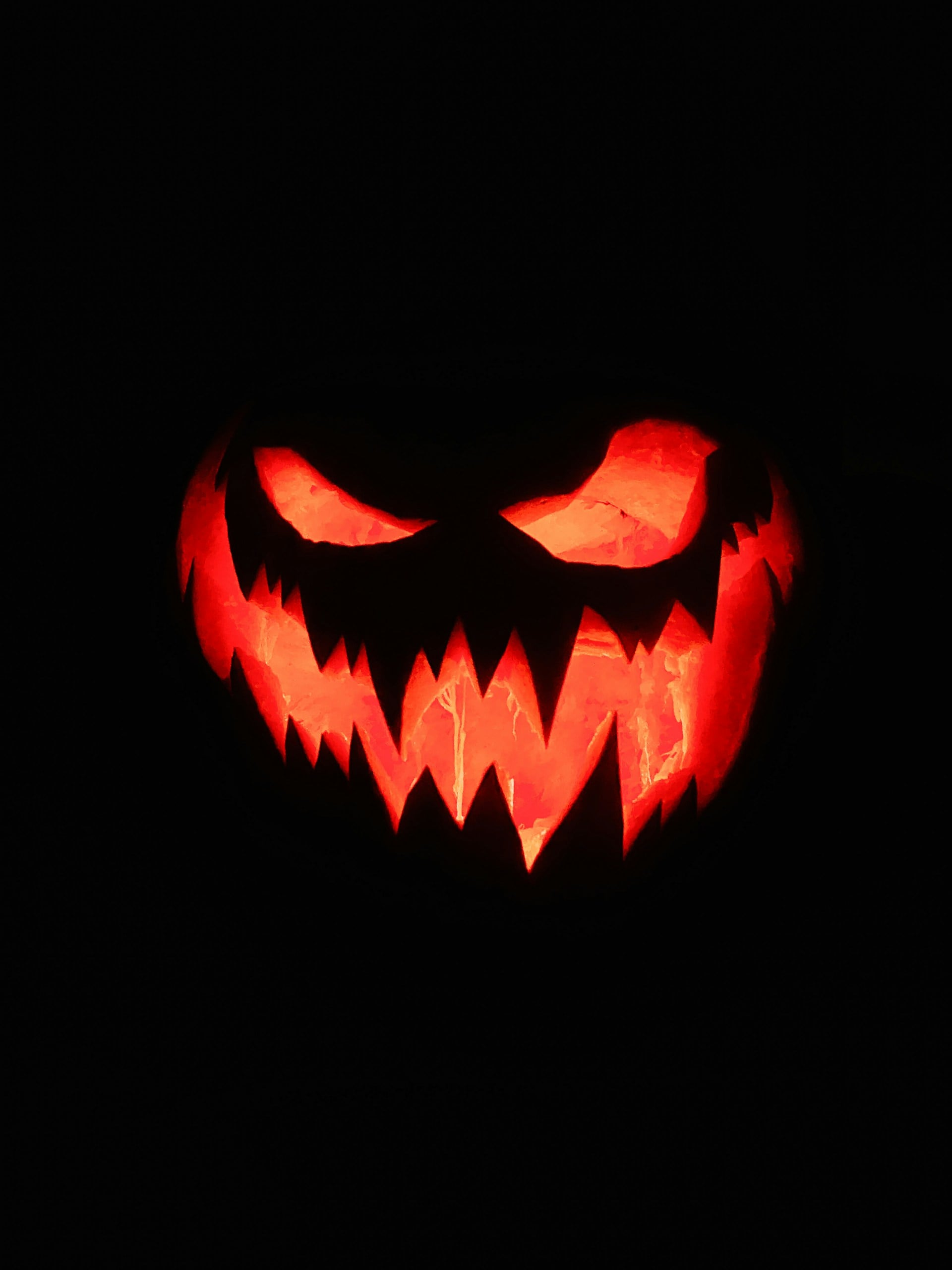 Glowing carved jack-o-lantern with a jagged toothy grin against a black background