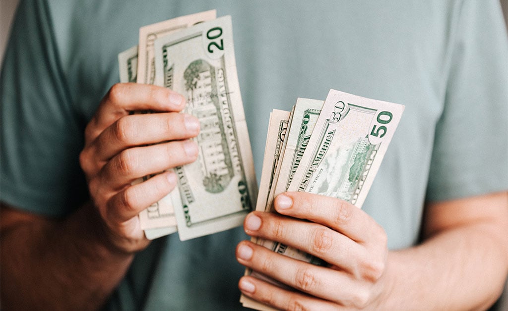 Person holding money they made off of weekend projects that added resale value to their home
