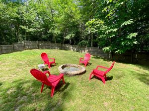 Backyard with red plastic chairs around a fire pit