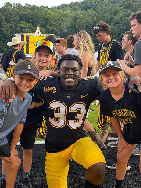 Appalachian State University football player posing with local kids at Kidd Brewer Stadium