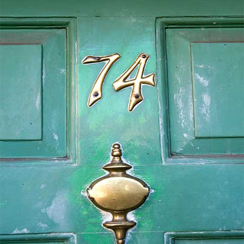 Blue door with gold address number 74 and door knocker