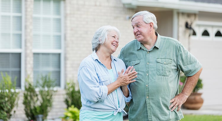 Senior couple standing in front of home