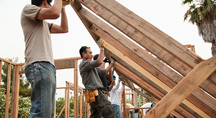 Construction workers lifting house frame