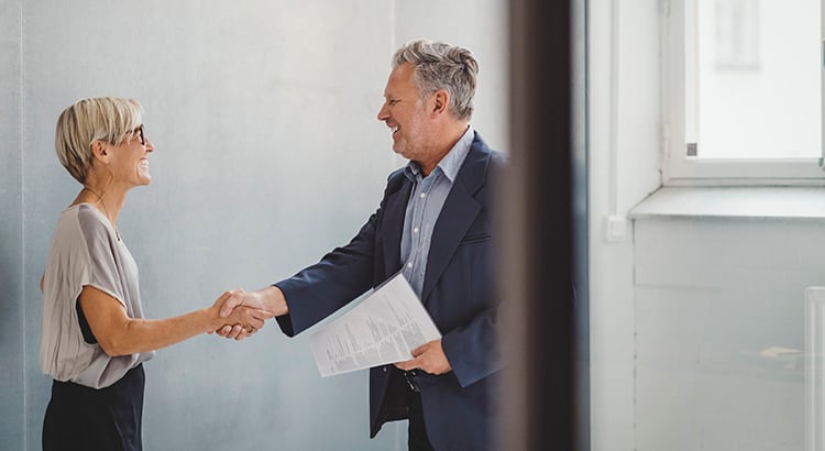 Mature businessman and businesswoman shaking hands in new office