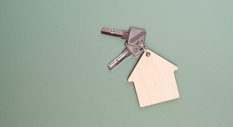 Keychain in form house with keys green background.Concept buying house, apartment or rent.
