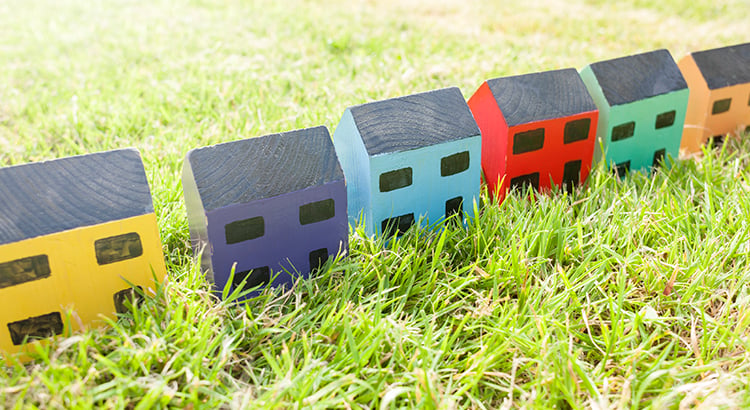 Row of wooden toy houses on grass