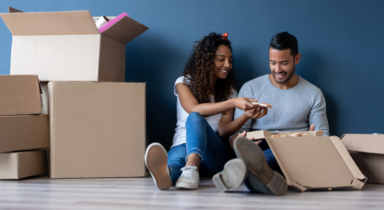 Young couple sitting on the floor amongst moving boxes.