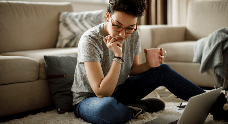 Woman on the floor in the living room with a coffee and laptop