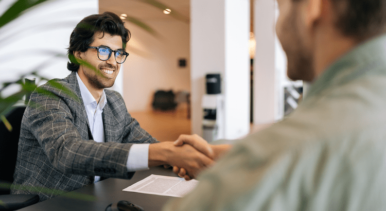 An agent shaking hands with a client after the contract is signed.