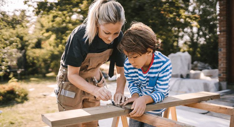 Mother and son cutting wood together.