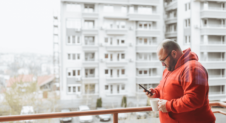 Man on a balcony looking at his phone.