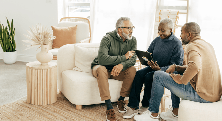 Three men sitting on a couch with an iPad.