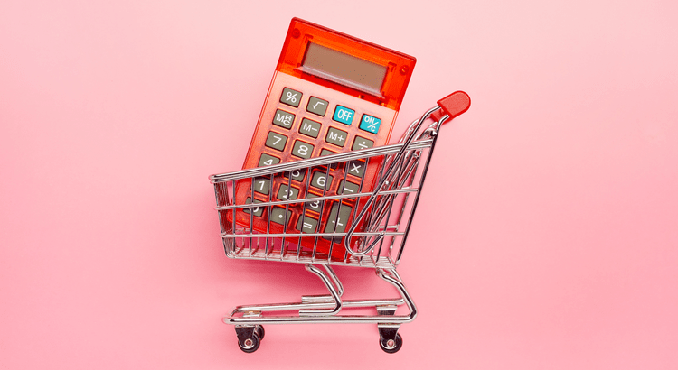 A calculator in a shopping cart with a pink background.