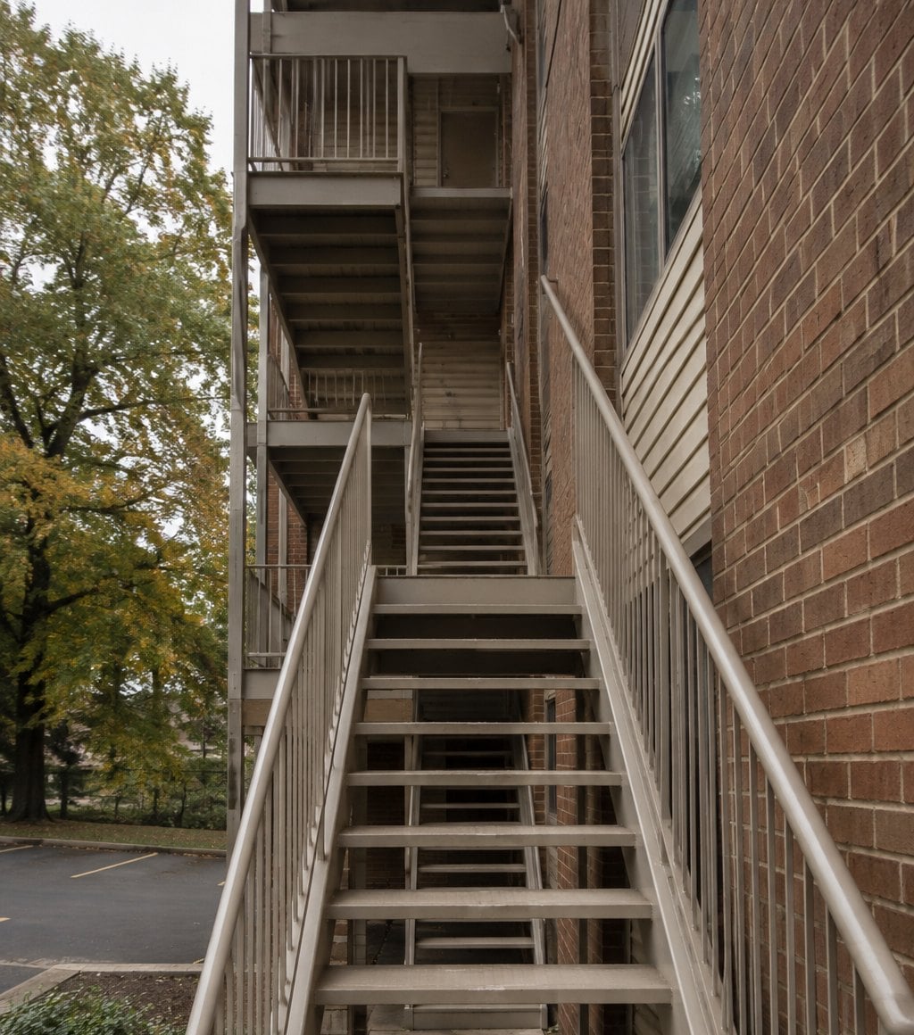 Exterior metal stairs climbing three flights to the upper floors of a four-story garden-style condominium building