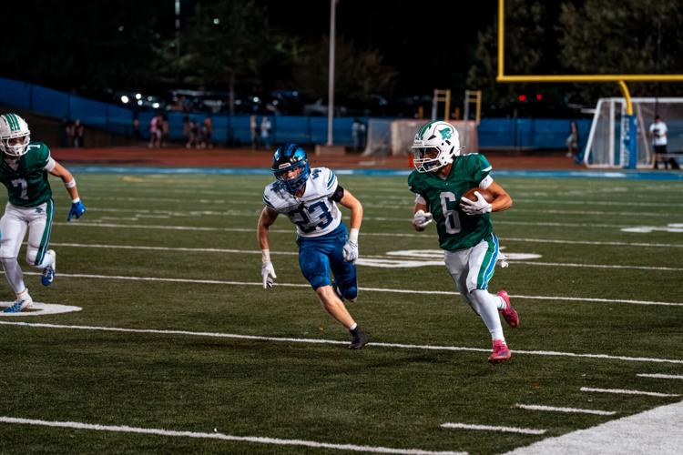 A South Lakes Seahawks football player carries the ball upfield during a night game at the school stadium in Reston, Virginia