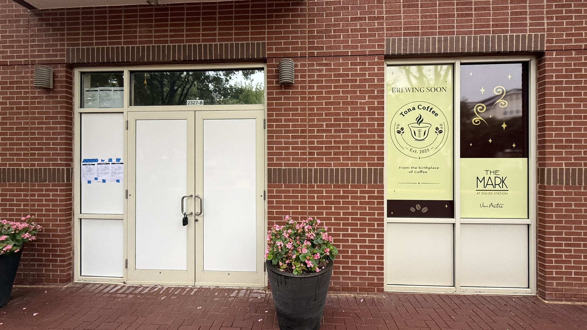 Storefront of Tona Coffee at 2327-B Dulles Station Boulevard in Herndon, with a Brewing Soon window sign beside The Mark at Dulles Station signage