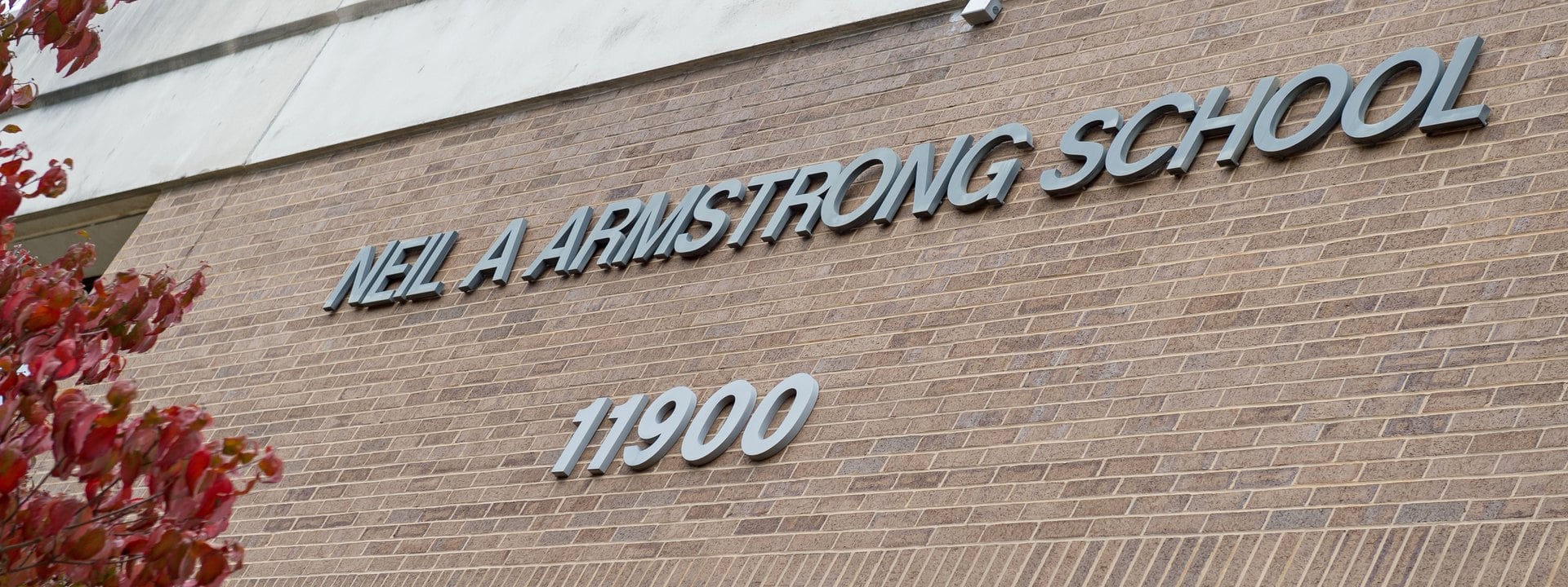Metal letters reading Neil A Armstrong School 11900 on the brick wall of Armstrong Elementary School in Reston, Virginia