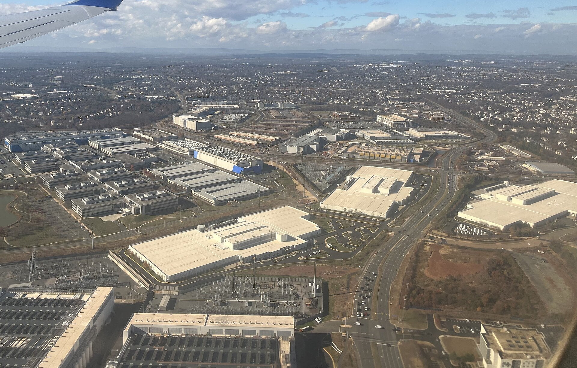 Aerial view of large data center buildings and electrical substations among commercial buildings near Ashburn in Loudoun County