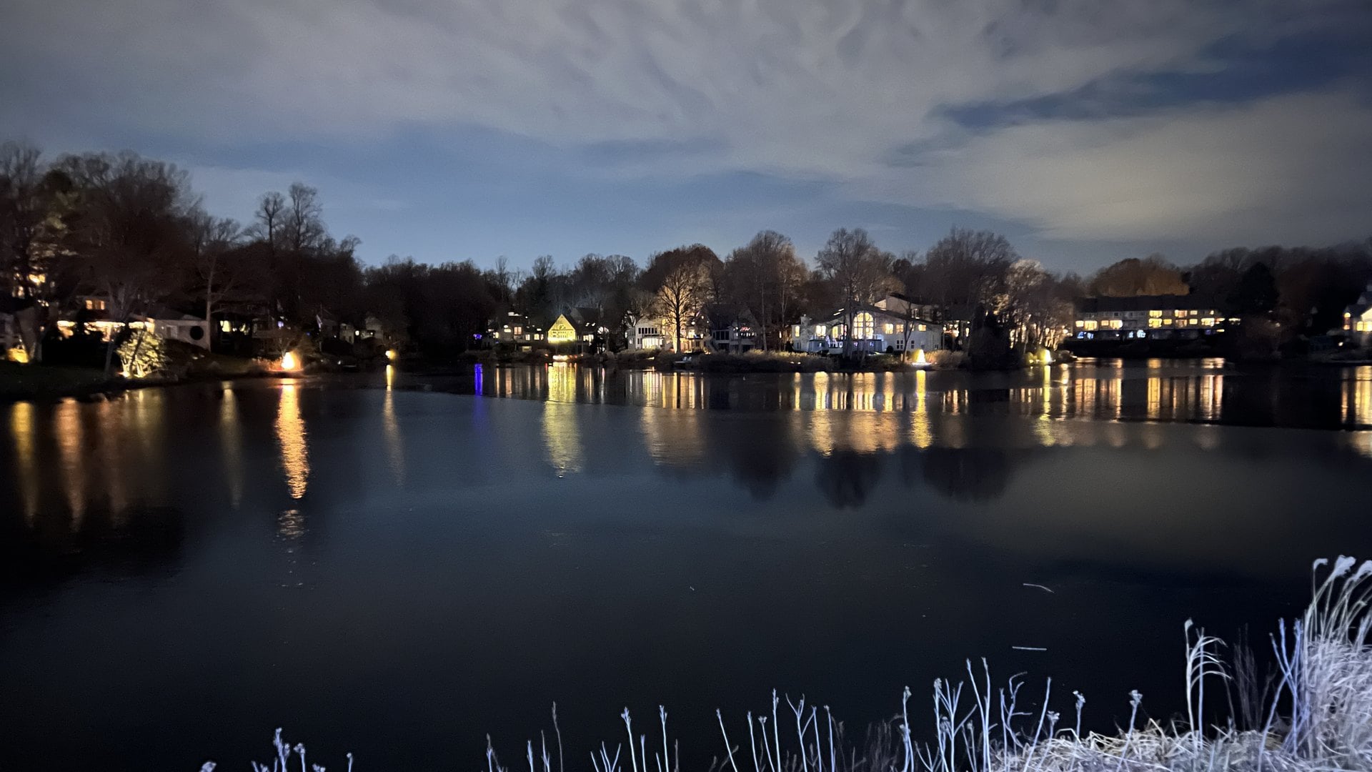 Lakefront homes reflected in still water at dusk during Winterfest in North Reston, Virginia