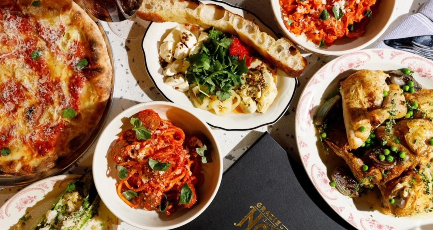 Overhead view of a table at Grazie Nonna with pizza, spaghetti and meatballs, pasta, roast chicken and focaccia