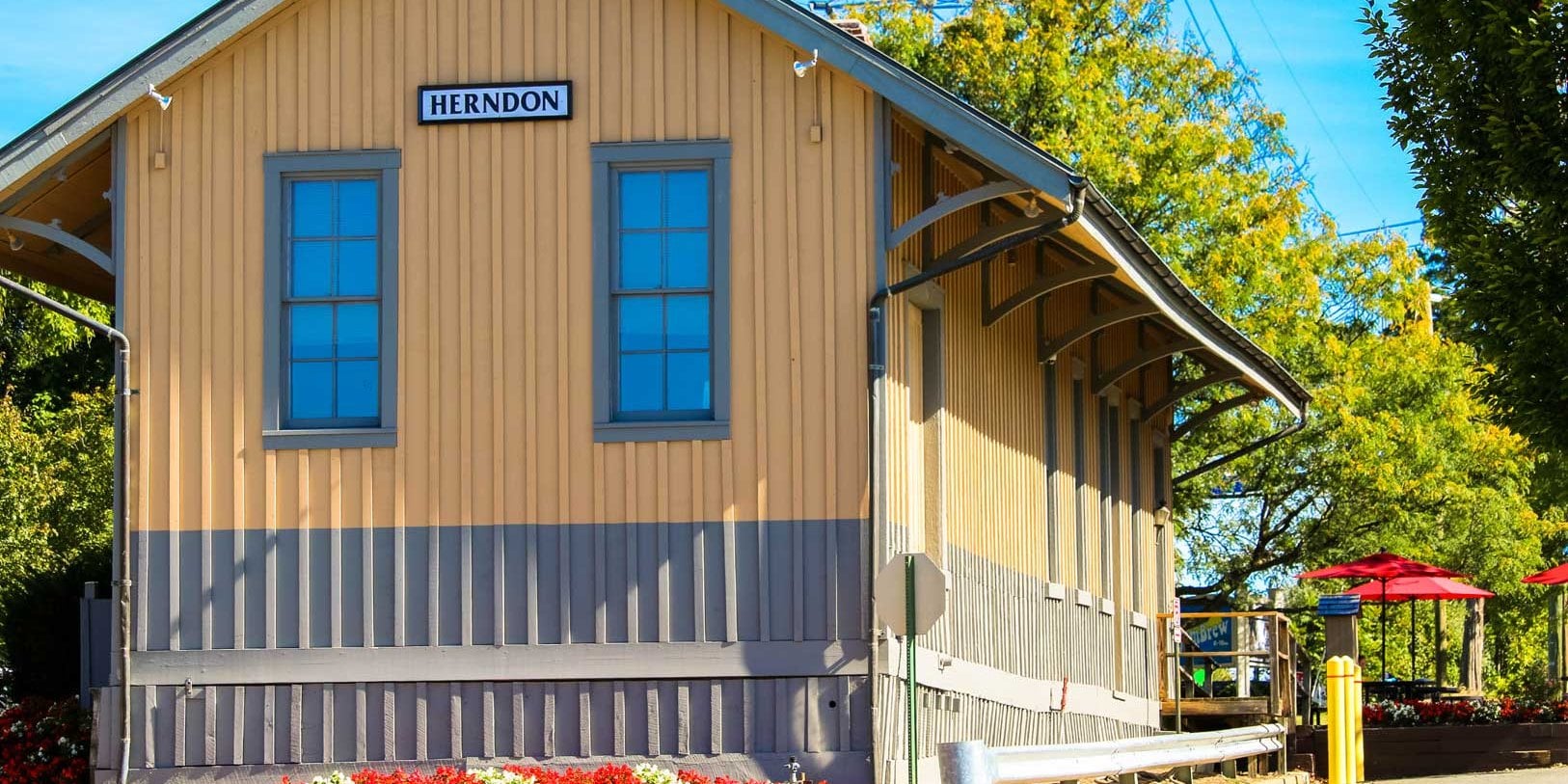 The yellow 1857 Herndon Depot with its Herndon sign beside the W&OD Trail in downtown Herndon, Virginia