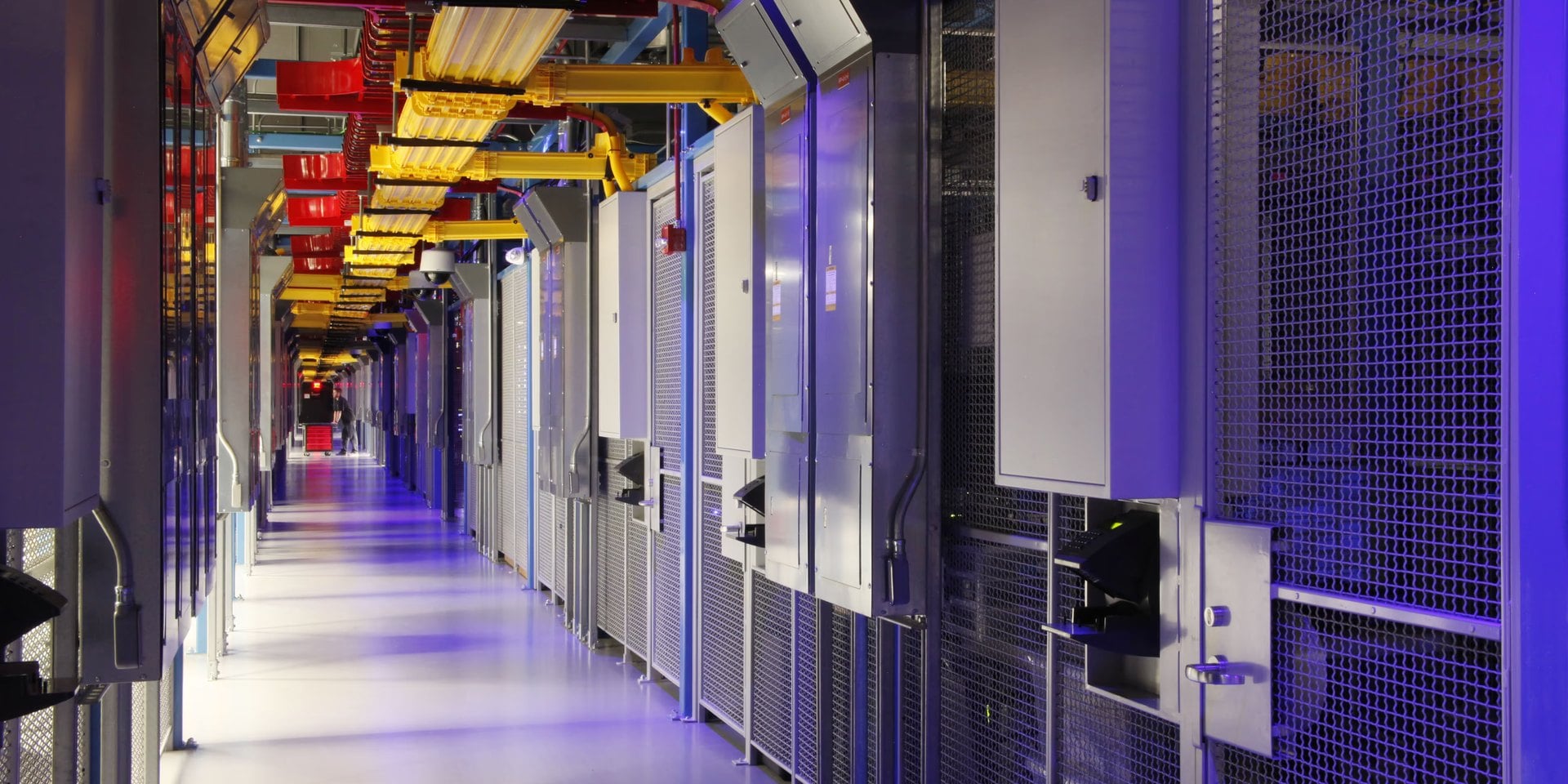 Corridor inside an Equinix data center in Dulles, Virginia, a TRINITY Group Construction project, with power panels, mesh cages and overhead cable trays