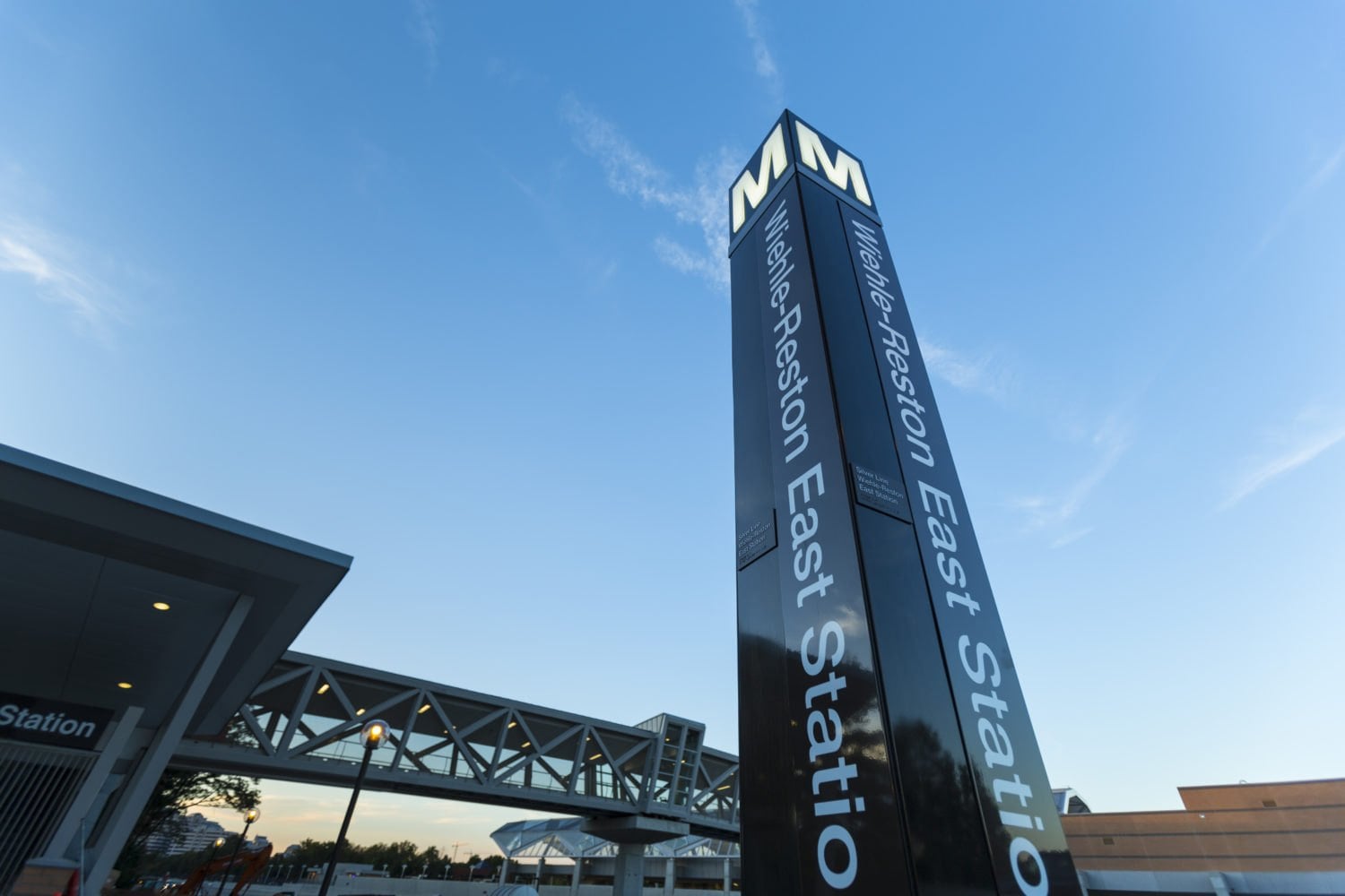 The Wiehle-Reston East Metro station pylon and pedestrian bridge against a blue evening sky in Reston, Virginia