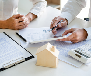 Real estate agents assisting clients in signing a property purchase agreement, representing the concept of buying real estate with professional guidance.