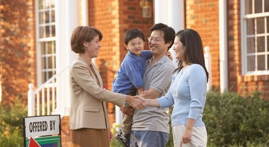 Real estate professional shaking hands with family who just bought new house