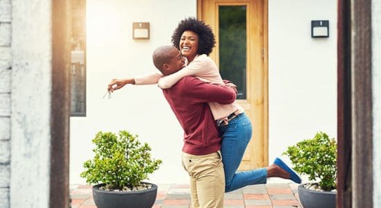 Young couple embracing each other in front on house