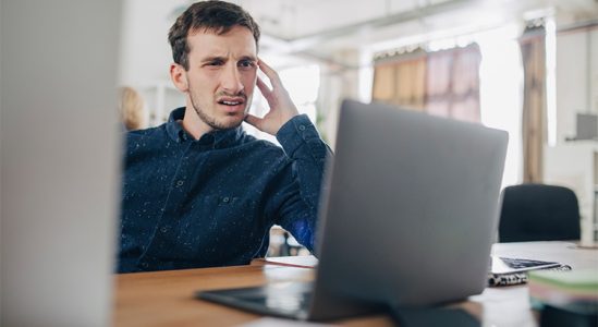 Man looking stressed while using laptop