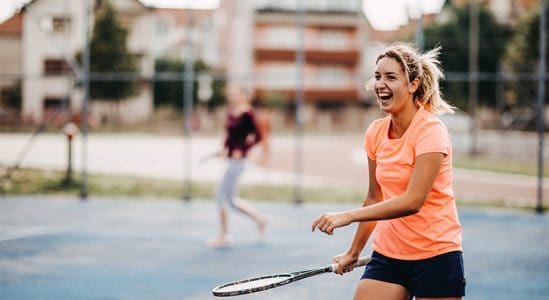 Young woman smiling while playing lawn tennis