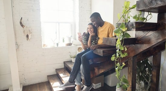 Young couple sitting in the stairs of their home