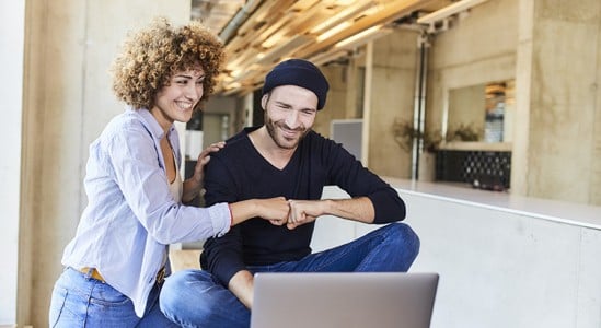 Couple smiling while looking at laptop