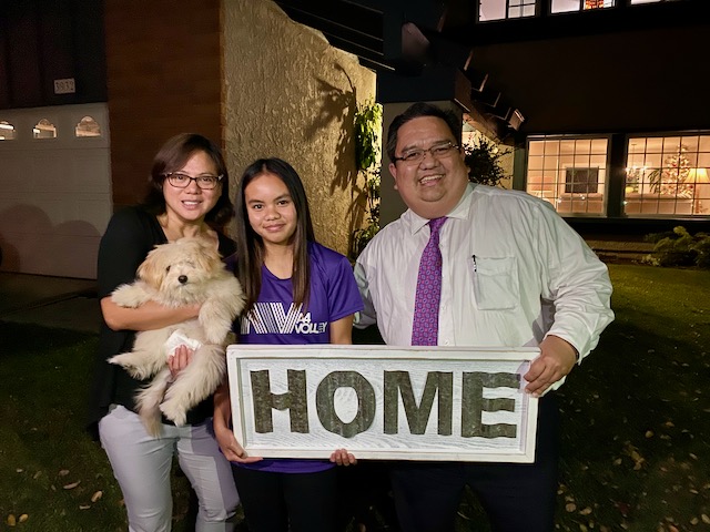 Client of Richard named Daniel and Alma holding a signage that says 'Home'