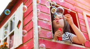Boy blowing bubbles in a wooden playhouse