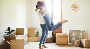 Happy couple in white t-shirts and blue jeans unpack boxes in their new home.