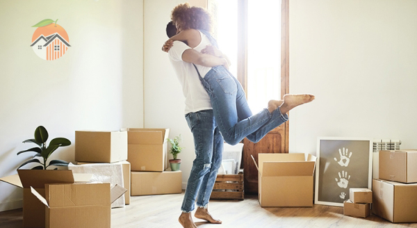 Happy couple in white t-shirts and blue jeans unpack boxes in their new home.