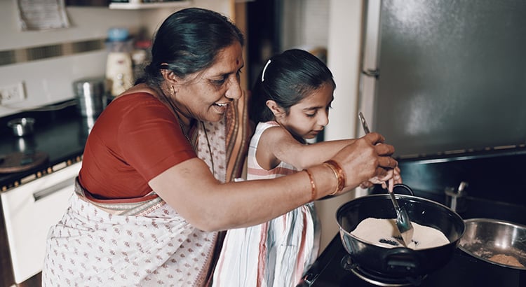 Young girl helping her grandmother while working in the kitchen