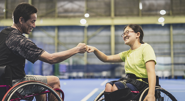 Disabled female athlete doing a fist bump with her coach during playing wheel chair tennis