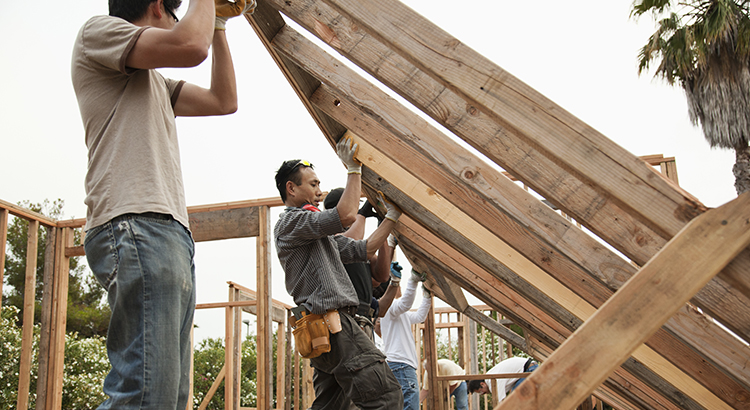 Construction workers lifting house frame