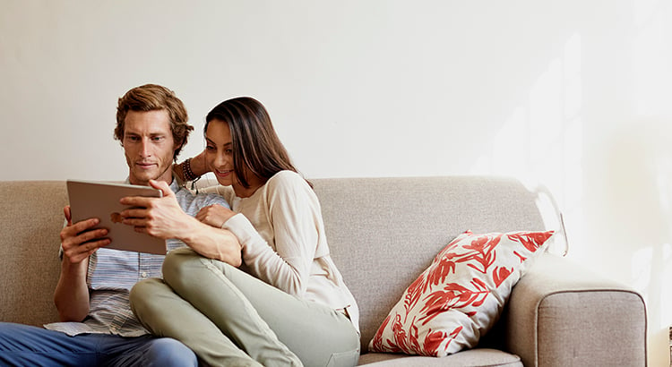 Couple using digital tablet on sofa at home