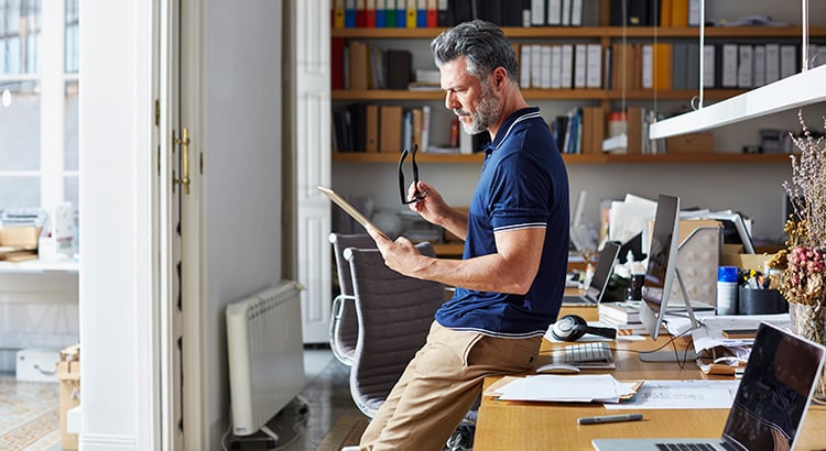 Businessman using digital tablet leaning on desk