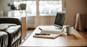 coffee, laptop and a white notebook with a pen ready to work at home